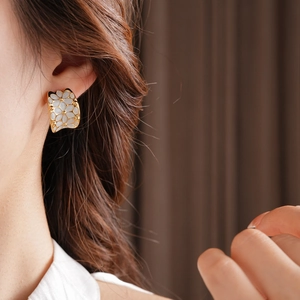 Gros plan d'élégantes boucles d'oreilles dorées en C avec pétales en émail blanc