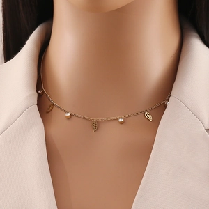 Detail of gold necklace with leaf pendants and round clear gemstones on a model