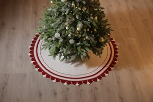 Dettaglio macro del tappeto per albero di Natale in maglia crema con bordi rossi ondulati