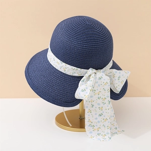 Detailed texture of navy wide brim straw sun hat with floral chiffon ribbon on gold stand