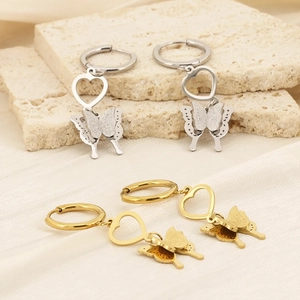 Macro detail of heart and butterfly drop earrings with textured frosted gold and silver finish