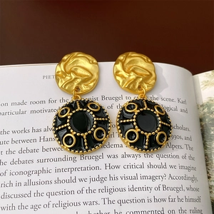 Vintage gold and black enamel flower drop earrings on an open book background