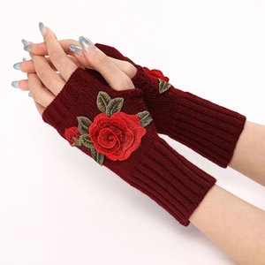 Detail of burgundy knitted fingerless gloves with elegant red rose embroidery and green leaves