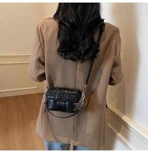 Détail du sac bandoulière tressé noir avec pendentif étoile et texte embossé sur la sangle