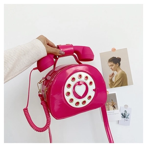 Macro view of a retro telephone shaped crossbody bag in glossy magenta patent leather