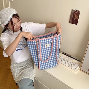 Nahaufnahme der blau karierten Canvas-Tasche mit rosa Paspelierung und Webetikett