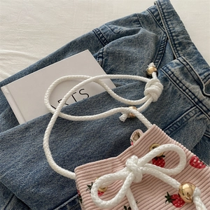 Borsa a secchiello in velluto rosa con fragole e chiusura a coulisse su jeans