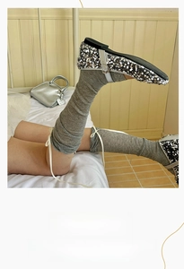 Detail of grey ribbed leg warmers with white ribbons and silver ballet flats