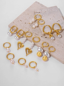 Close-up of gold-plated tassel earrings with pearls on stone texture background