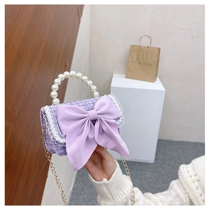 Detail of purple tweed girls bag with large bow, pearl handle, and golden chain strap
