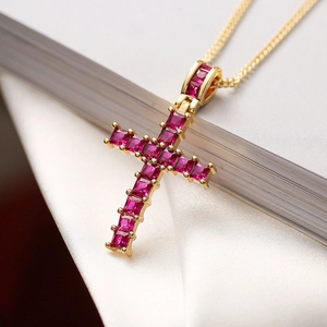 Macro shot of gold-plated geometric cross pendant with inlaid red square gemstones