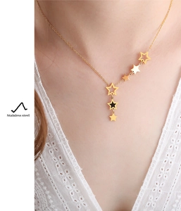 Close-up of a gold stainless steel star cluster pendant necklace worn by a model