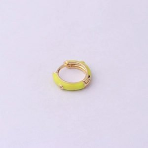 Macro view of golden hoop earring with yellow enamel coating and sparkling zircon stones
