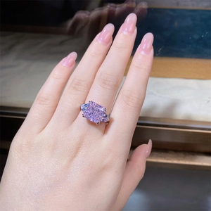 Gros plan d'une bague avec pierre rose de 5ct taille radiant et diamants poire sur le doigt