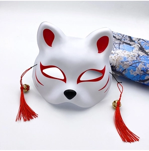 Detail of hand-painted white Japanese kitsune mask with red tassels and golden bells