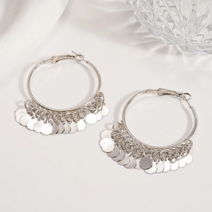 Macro detail of silver layered disc hoop earrings on a minimalist decorative background