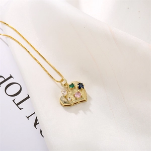 Detail of gold heart pendant with multi-color gemstones on white pleated fabric