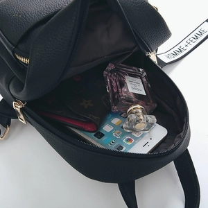 Mini black pebbled leather backpack with logo straps and open zipper showing interior