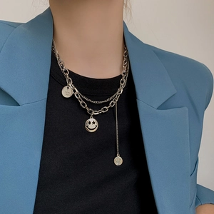 Detail of layered silver necklaces with a round Love You pendant and smiley face charm