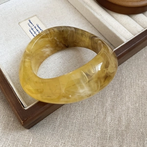 Close-up of amber marble resin bangle presented in a premium wooden jewelry display box