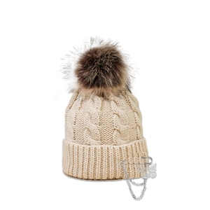 Detailed macro view of the beige cable-knit texture with silver butterfly pin and chain