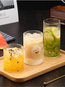 Tres vasos de vidrio estriado con café y té sobre una bandeja de madera decorada
