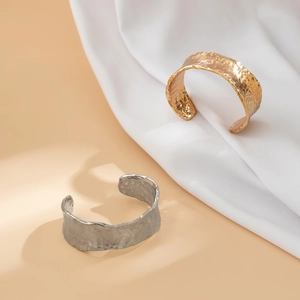 Chic gold and silver wide open cuffs with hammered texture on white silk background