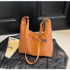 Detail of orange nylon tote bag with leather Fashion tag and adjustable wide shoulder strap