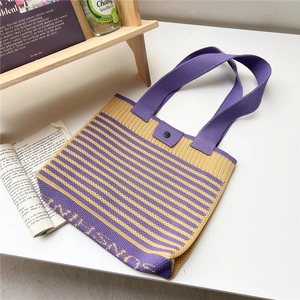 Detail of yellow and purple striped knit tote bag with snap closure and wide handle