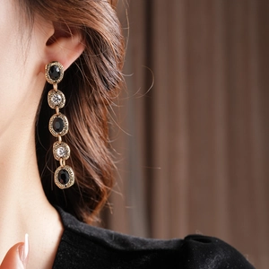 Gros plan de boucles d'oreilles vintage dorées avec strass noirs et clairs sur mannequin