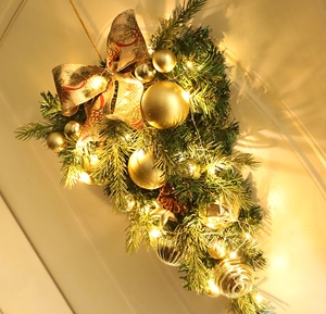 Detailansicht eines Weihnachts-Türhänger mit goldenen Kugeln, Schleife und LED-Licht
