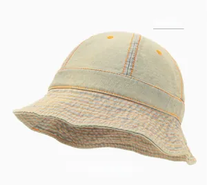 Détail d'un bob en jean délavé avec surpiqûres orange contrastées et œillets d'aération
