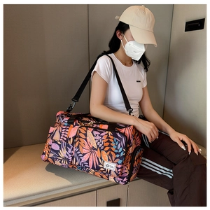 Detail of a large capacity travel bag with colorful leaf print and adjustable straps