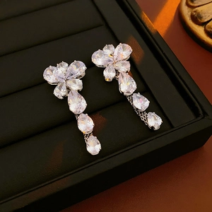 Detail of silver drop earrings with floral zircon stones set in a black jewelry box