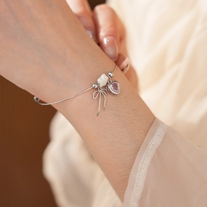 Close-up of bow bracelet featuring pink heart zircon and white mother of pearl details