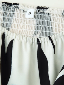 Close-up of zebra print dress neckline with elastic smocked fabric and size S label