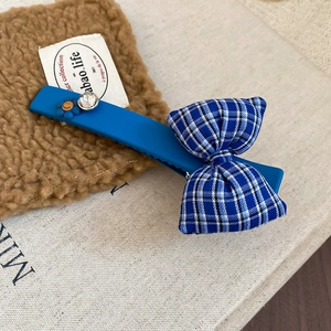 Detail of blue matte hair clip with checkered bow, rhinestone, and smiley flower