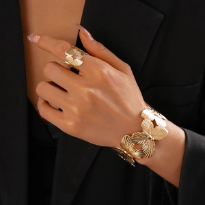 Detail of gold butterfly cuff bracelet and ring set with brushed metal texture on wrist