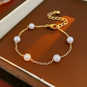 Detail of elegant gold chain bracelet featuring six white pearls and adjustable clasp