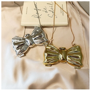 Detailed close-up of metallic bow clutch bags in gold and silver with elegant chain straps