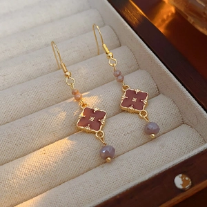Macro shot of vintage gold earrings with burgundy flower and purple beads in a jewelry box