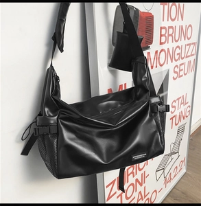 Close-up of black PU leather crossbody bag featuring mesh side pockets and adjustable strap
