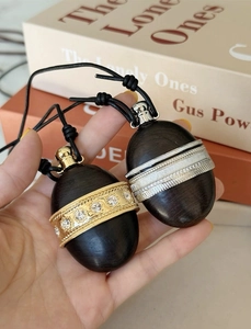 Detailed view of wood oval pendants with crystal-set gold and silver bands on leather cord