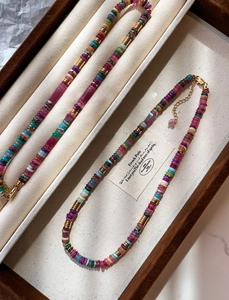 Detail of 18k gold plated beaded necklace with colorful natural gemstones and heart charm