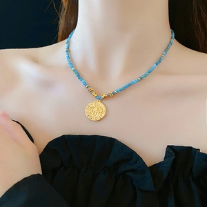 Macro detail of bohemian beaded necklace with golden evil eye pendant and blue beads