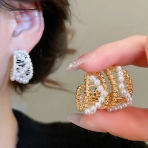 Macro detail of 18k gold plated C-shaped hoop earrings with woven pearl embellishments