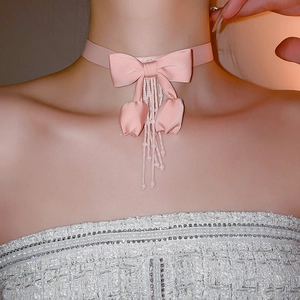 Close-up of elegant pink ribbon choker with bow and beaded tassels on a model