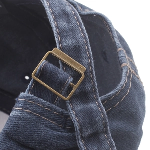 Detail of adjustable bronze metal slide buckle on vintage washed denim baseball cap