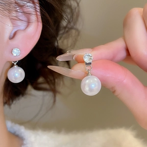 Close-up of vintage silver needle earrings with large pearls and zircon detailing