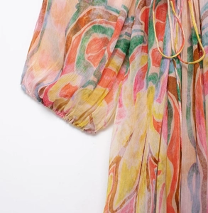 Detail of colorful printed chiffon dress featuring lantern sleeves and tie-neck closure